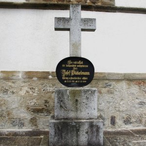 Grabkreuz an der Kirchenmauer