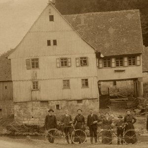 Bauern mit Fahrrädern vor Bauernhof