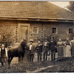 Bauernfamilie vor hölzernem Bauernhaus