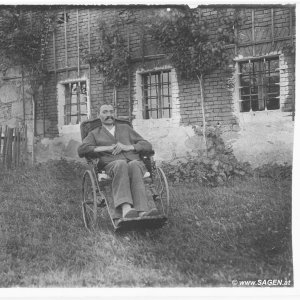 Im Rollstuhl vor dem Bauernhaus.